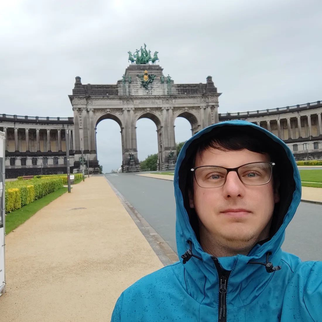 Adam w kapturze przed łukiem triumfalnym w parku Cinquantenaire