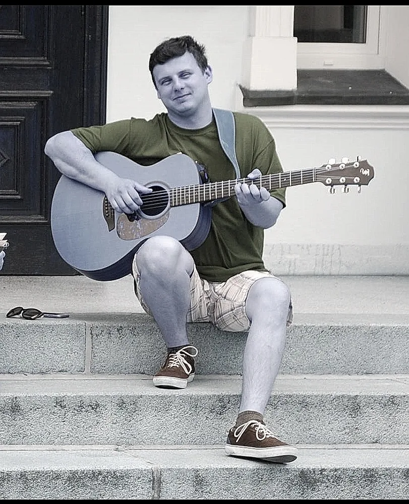 Adam z gitarą akustyczną na schodach