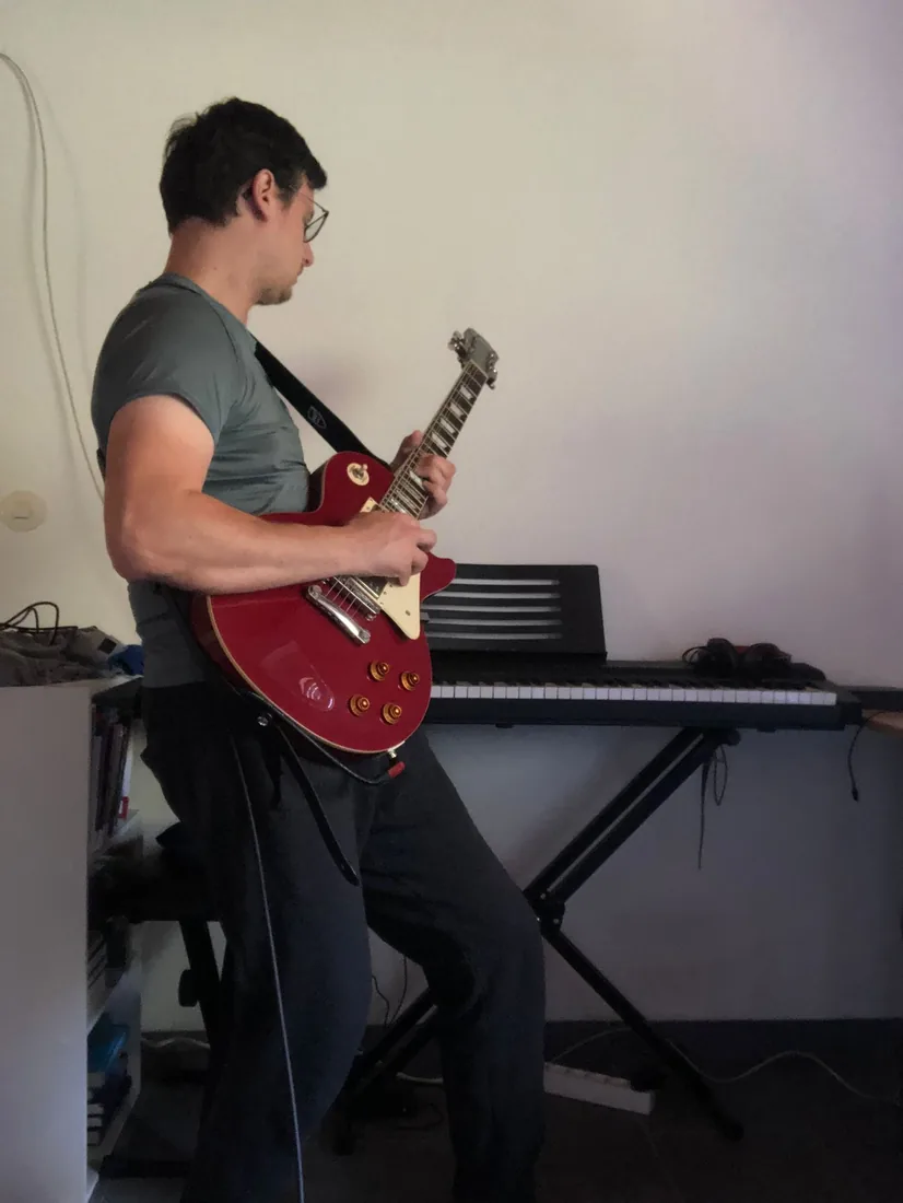 Adam gra na czerwonym Les Paulu przy keyboardzie