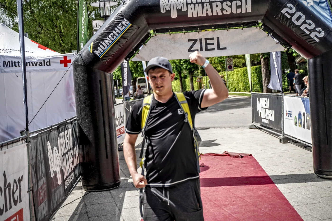 Adam z uniesioną pięścią pod bramą z napisem ZIEL