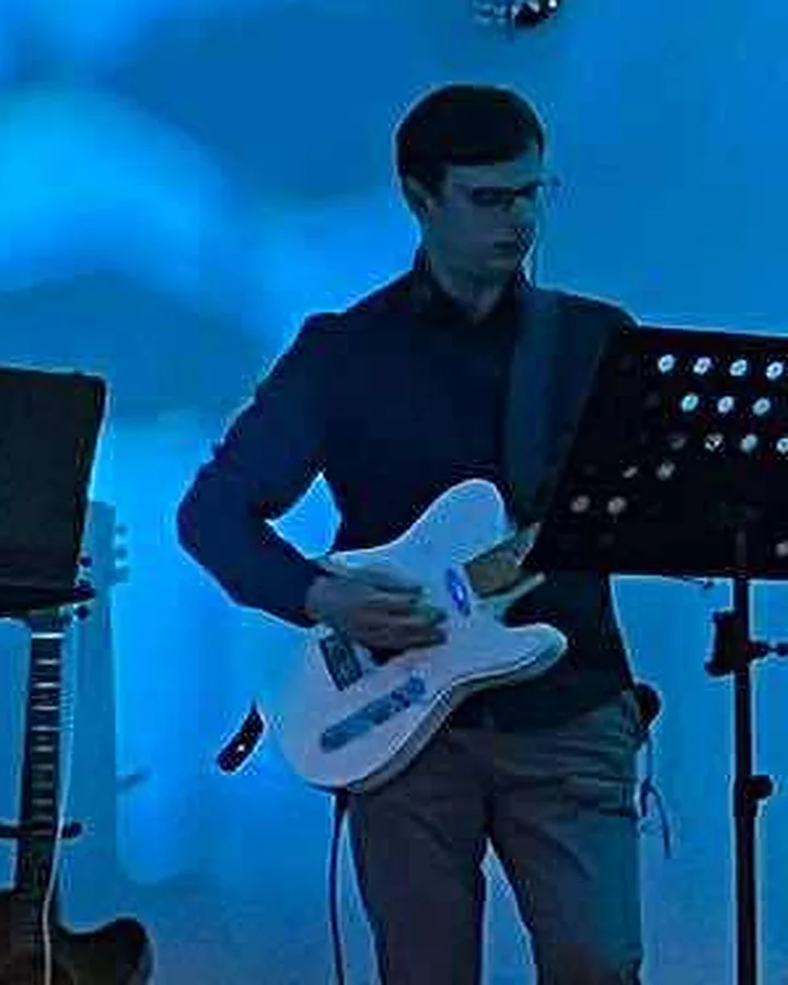 Adam z gitarą Telecaster na koncercie Zaduszek w sali, w niebieskim świetle