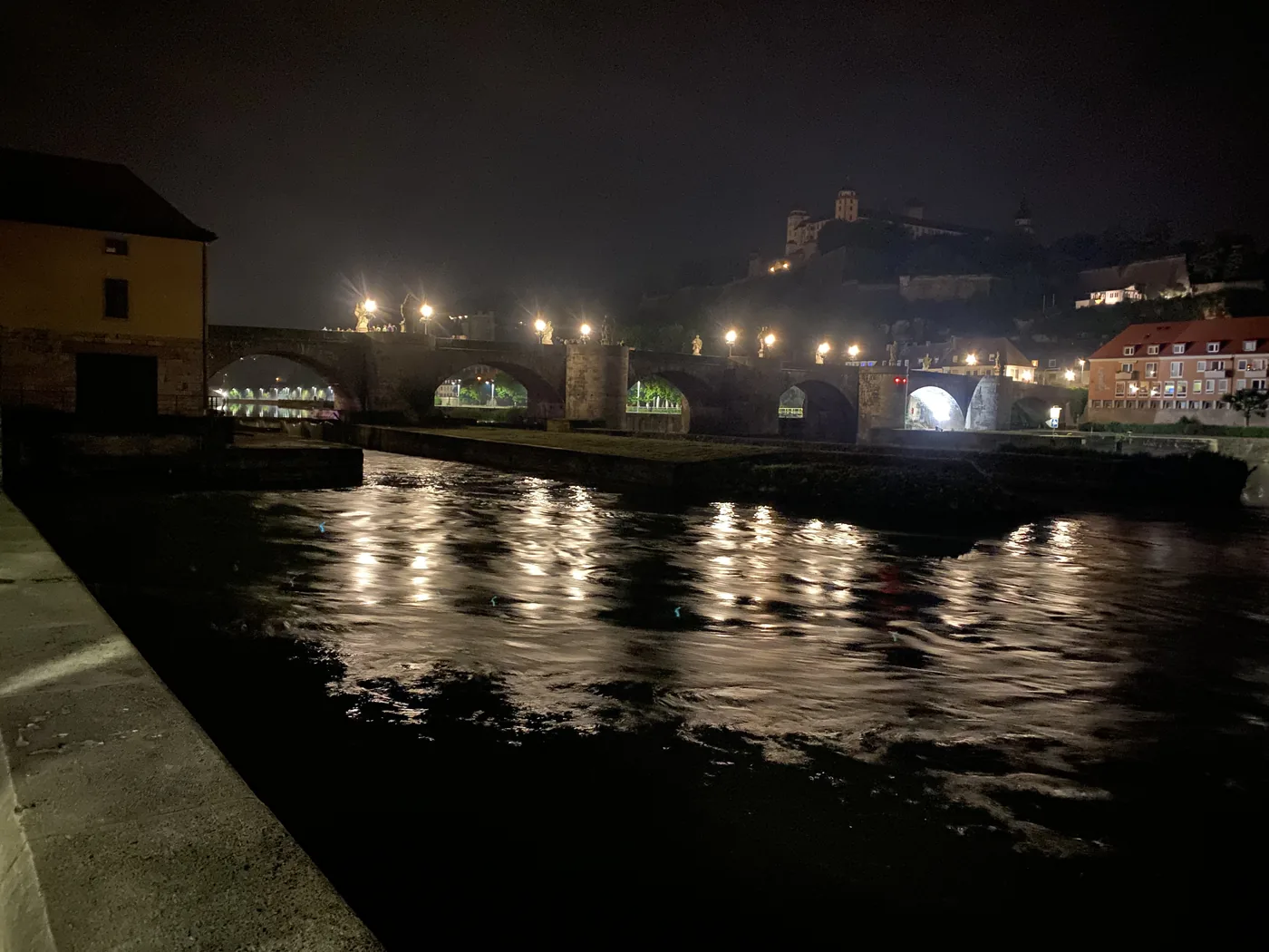 Oświetlony Stary Most na Menem w Würzburgu nocą, nad nim twierdza na wzgórzu