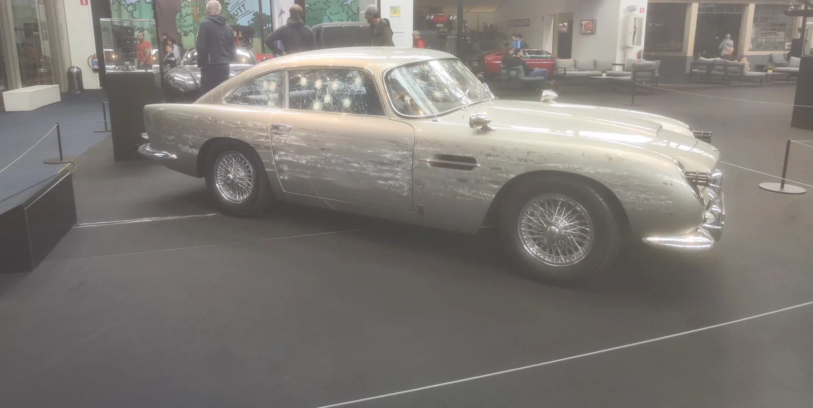 Srebrny Aston Martin DB5 z dziurami po kulach na karoserii